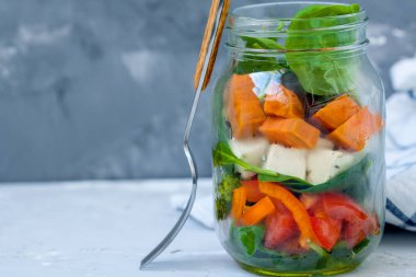 Bir kavanoza vegan salata: ıspanak, sebze, soya peyniri, brokoli ve tatlı patates.