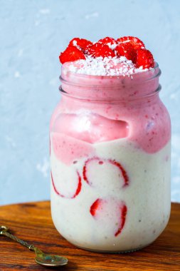 Parlak yaz çilek muz yüzlü bir kavanoz içinde Hindistan cevizi ile.