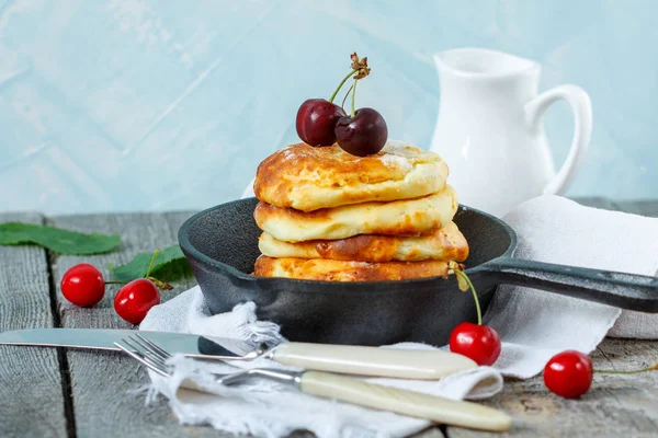 Panqueques caseros de requesón con cerezas en una sartén de hierro fundido . — Foto de Stock