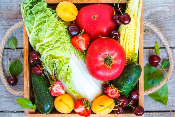 Summer fruits and vegetables in a wooden box.