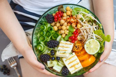 Çocuk bir vegan kase elinde tutuyor. 