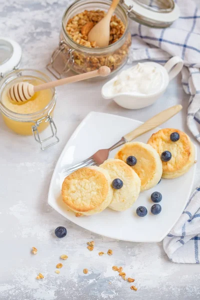 Творожные пирожные и мюсли с мёдом, йогуртом, сметаной и — стоковое фото