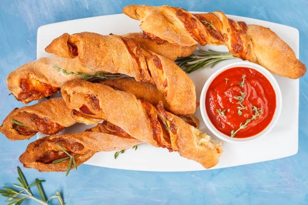 Tasty cheese sticks with bacon, herbs and tomato sauce. Top view