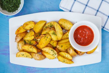 Fırında patates dilimleri ile beyaz bir tabak içinde otlar