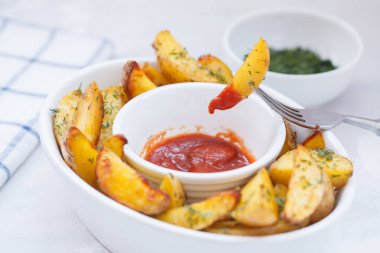 Fırında patates dilimleri ile beyaz bir tabak içinde otlar