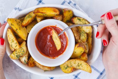 patates dilimleri ile domates soslu beyaz bir tabak içinde otlar pişmiş