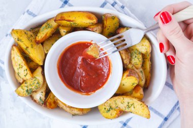 patates dilimleri ile domates soslu beyaz bir tabak içinde otlar pişmiş