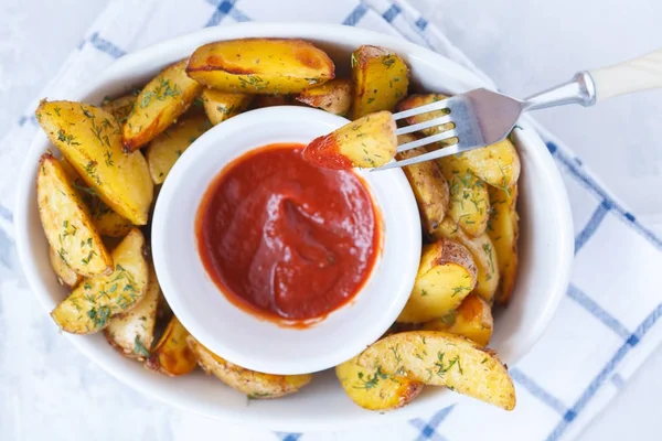 Baked potato slices with herbs in a white dish with tomato sauce