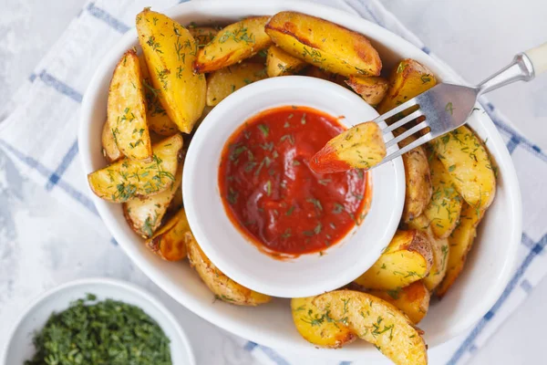 patates dilimleri ile domates soslu beyaz bir tabak içinde otlar pişmiş