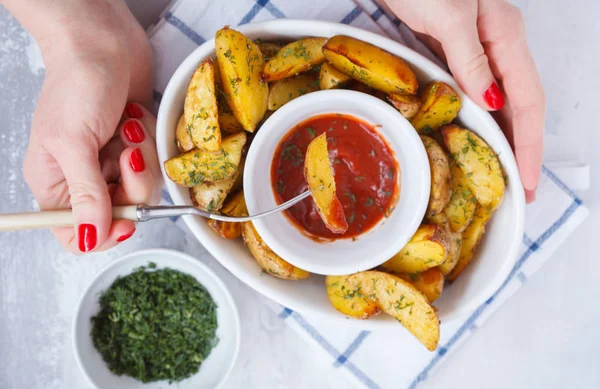 baked potato slices with herbs in a white dish with tomato sauce