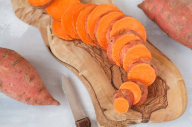Ham taze dilimlenmiş tatlı patates ahşap oyun tahtası. 