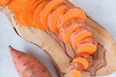 Ham taze dilimlenmiş tatlı patates ahşap oyun tahtası. 