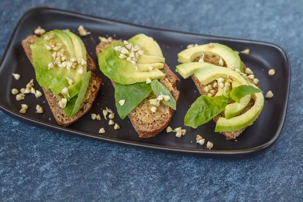 Avocado-Sandwich mit Basilikum und Sprossen aus grünem Buchweizen auf einem — Stockfoto