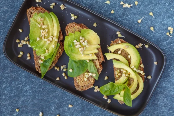 Avocado-Sandwich mit Basilikum und Sprossen aus grünem Buchweizen auf einem — Stockfoto