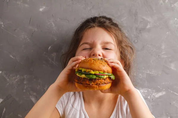 A menina está comendo um saudável assado hambúrguer de batata doce wi — Fotografia de Stock
