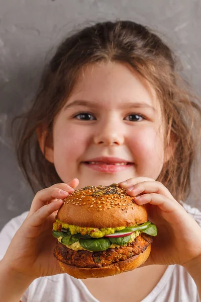 Den lille pige spiser en sund bagt sød kartoffel burger wi - Stock-foto