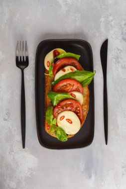 Mozzarella peyniri, domates ve fesleğen üzerinde siyah bir di Caprese sandviç