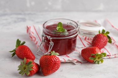 Çilek, gri arka plan ile cam kavanozda çilek reçeli.