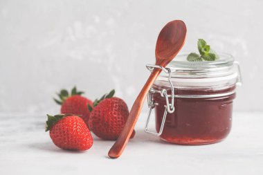 Çilek, gri arka plan ile cam kavanozda çilek reçeli.