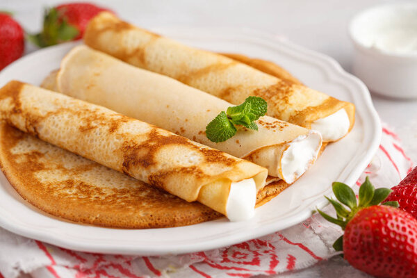 Thin hot pancakes with cottage cheese and strawberries.