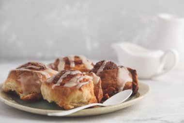 Ev yapımı tarçınlı çörek hafif bir plaka üzerinde sır, backgrou ışık