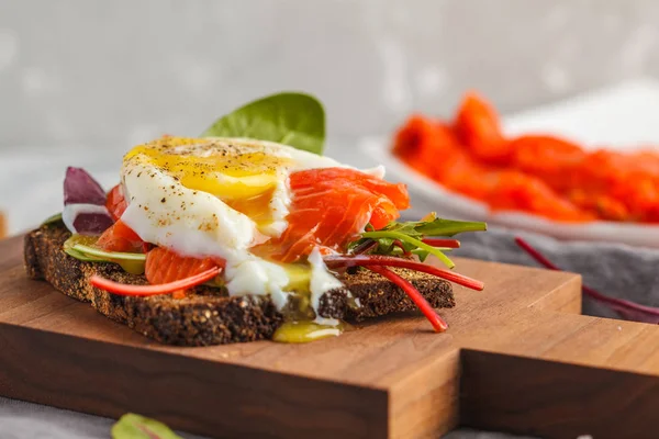 Panino fresco con uovo in camicia, trota di pesce rosso sul pane di segale . — Foto Stock