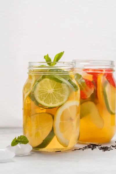 Fruit ice tea and ginger herbal ice tea with mint in glass jars,