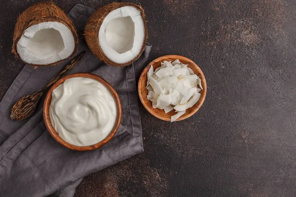 Iogurte de coco em uma tigela de madeira em um fundo escuro, vista superior , — Fotografia de Stock