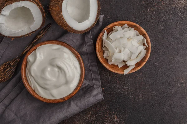 Iogurte de coco em uma tigela de madeira em um fundo escuro, vista superior , — Fotografia de Stock