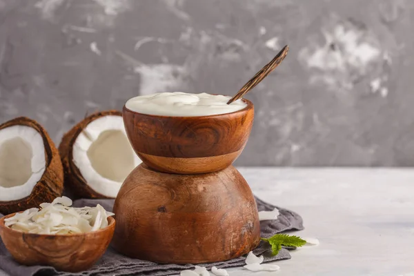 Iogurte de coco em uma tigela de madeira em um fundo escuro, espaço de cópia — Fotografia de Stock