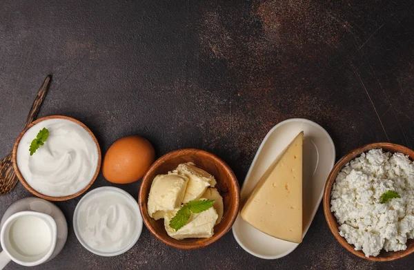 Different types of dairy products on dark background, top view,