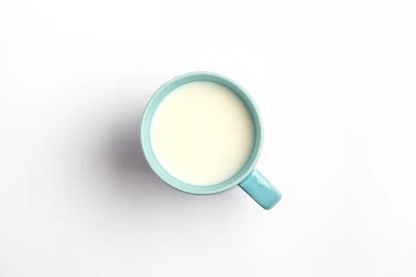 Mleko w niebieski kubek na białym tle na białym tle, widok z góry. — Zdjęcie stockowe