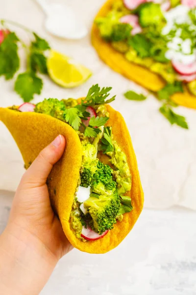 Vegan açafrão tacos com rabanete, brócolis e guacamole na mão — Fotografia de Stock