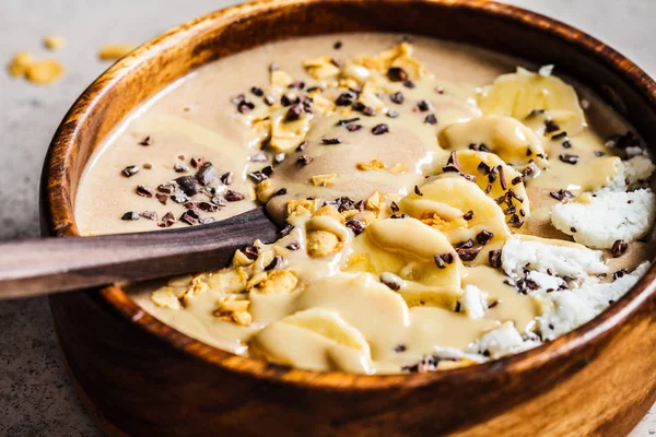 Chocolate smoothie bowl with coconut chips, banana and cocoa nibs
