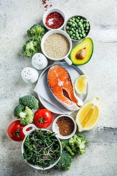 Raw salmon with broccoli, quinoa and avocado on gray background