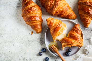 Yaban mersinli taze kruvasan ve bal, gri arka plan..