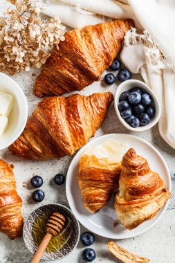 Yaban mersinli taze kruvasan ve bal, gri arka plan, üst manzara..