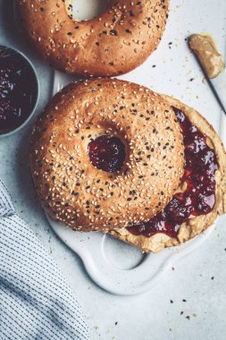 Beyaz tahtada fıstık ezmeli ve çilekli simit. Vejetaryen gıda konsepti.