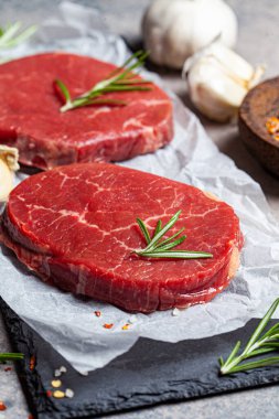 Baharatlı bir tahta üzerinde çiğ biftek fileto. Arka planda çiğ biftek bifteği.