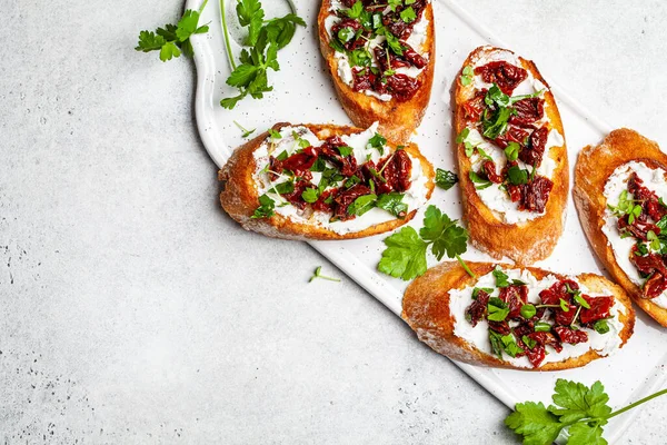 Beyaz bir tahta üzerinde güneşte kurutulmuş domates ve krem peynirli tost..