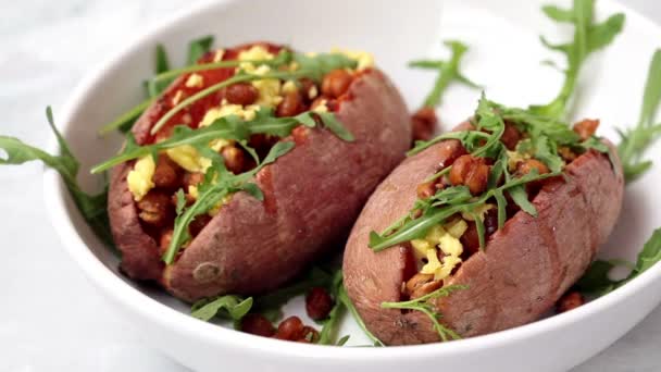 Gebackene Süßkartoffeln gefüllt mit gebratenen Kichererbsen und veganem Käse in einer weißen Schüssel. Konzept einer gesunden vegetarischen Ernährung. — Stockvideo