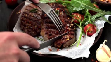 Ahşap tabakta roka ve domates salatası ile ızgara biftek kesme, arka plan koyu.