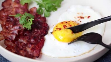 Keto kahvaltısı - sahanda yumurta, avokado ve beyaz tabakta kızarmış domuz pastırması. Keto diyet kavramı.