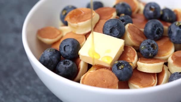 Cereales para panqueques con almíbar, mantequilla y bayas en un tazón blanco, panqueques pequeños — Vídeos de Stock