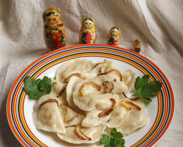 Russian vareniki with potato with matreshkas on the background — Stock Photo, Image