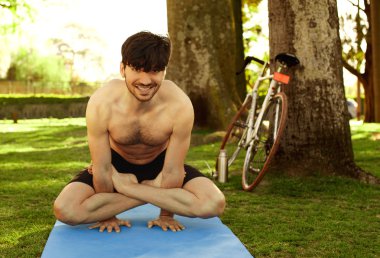 Yoga duruş çim yapan genç erkek 