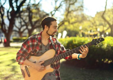 Adam parkta bas gitar çalmaya