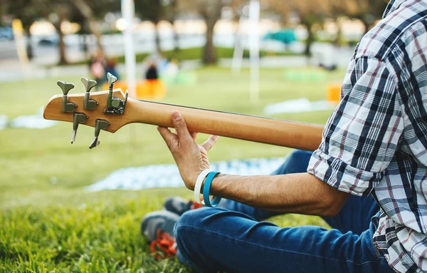 Ruka muže, hraje na kytaru sedět na trávě — Stock fotografie