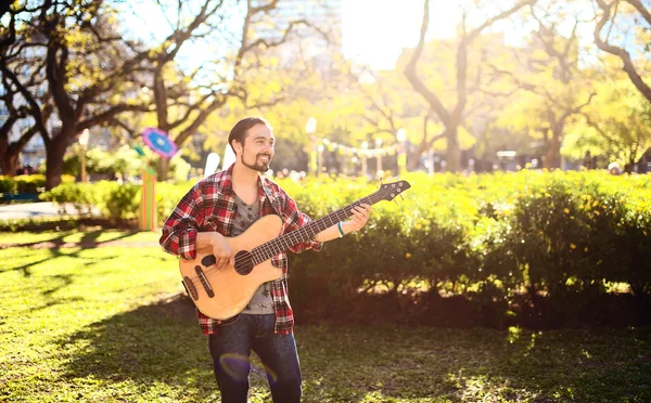 Genç adam parkta akustik bas gitar çalmaya