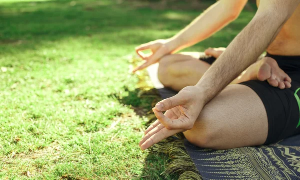 Eller ve ayaklar çimenlerin üzerinde meditasyon adam